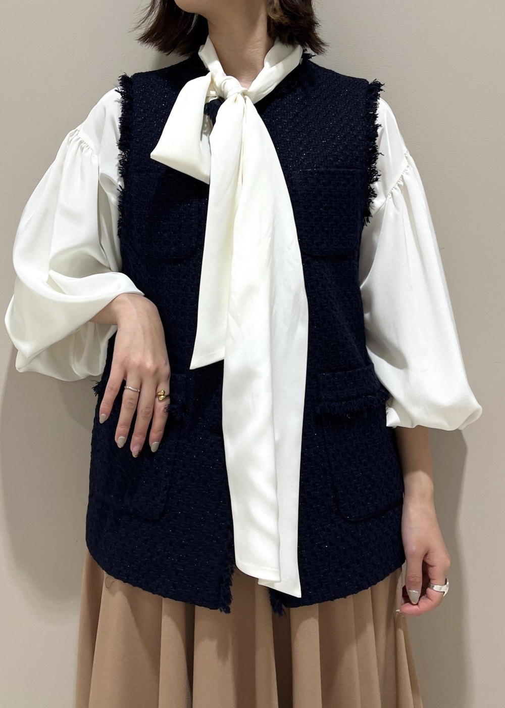 ベージュ系のパンプス、ベージュ系のハンドバッグ、イエロー系のスカートを着用したレディースの冬コーディネートの4枚目の写真