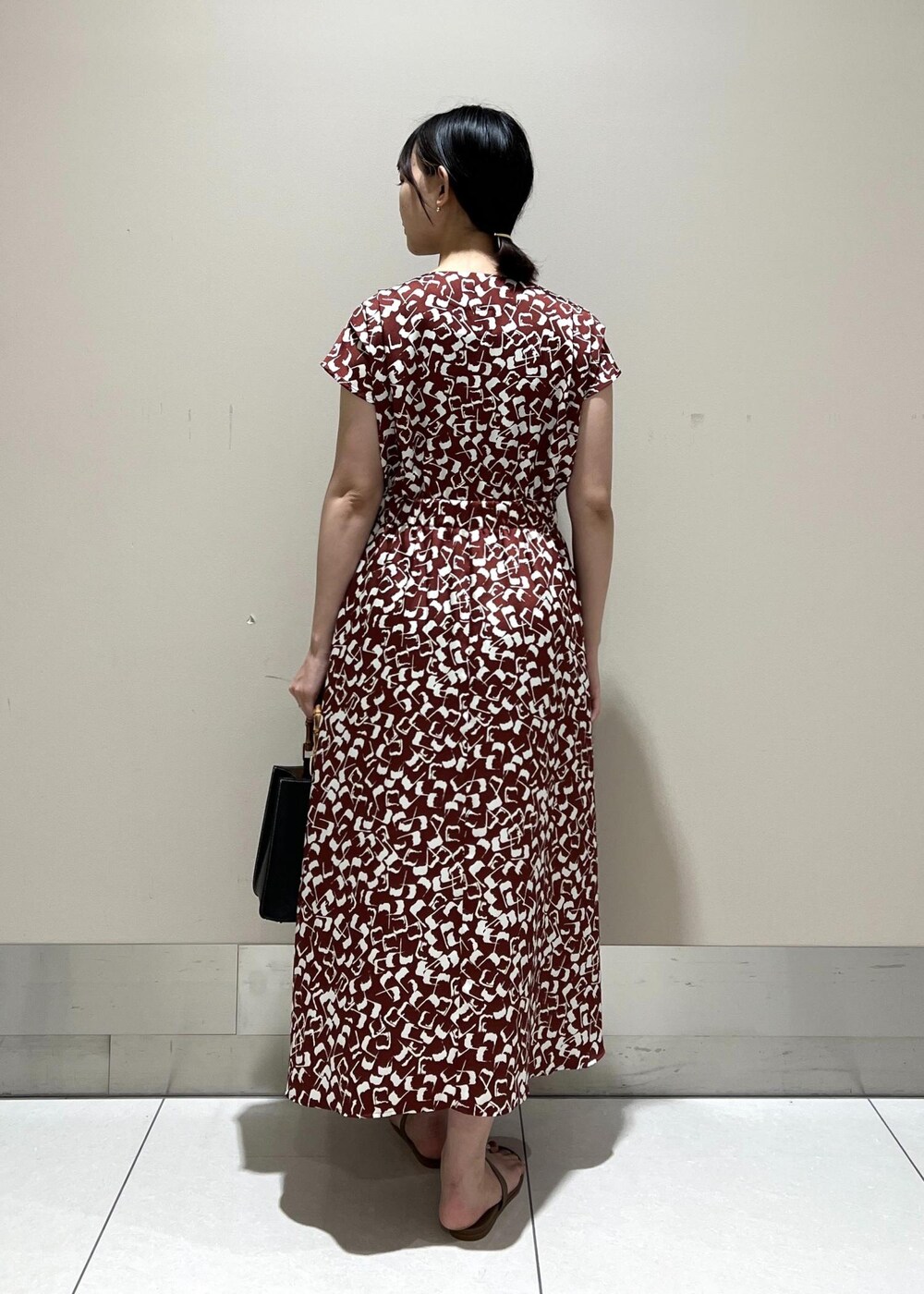 ブラック系のハンドバッグ、ベージュ系のサンダル、レッド系のワンピースを着用したレディースの夏コーディネートの3枚目の写真