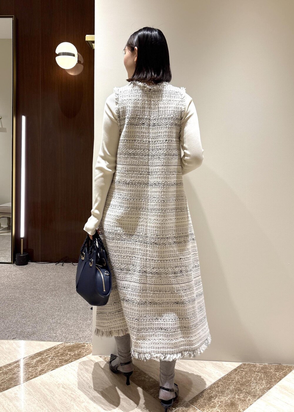 ブラック系のパンプス、ホワイト系のワンピース、ホワイト系のニット/セーターを着用したレディースの春コーディネートの4枚目の写真