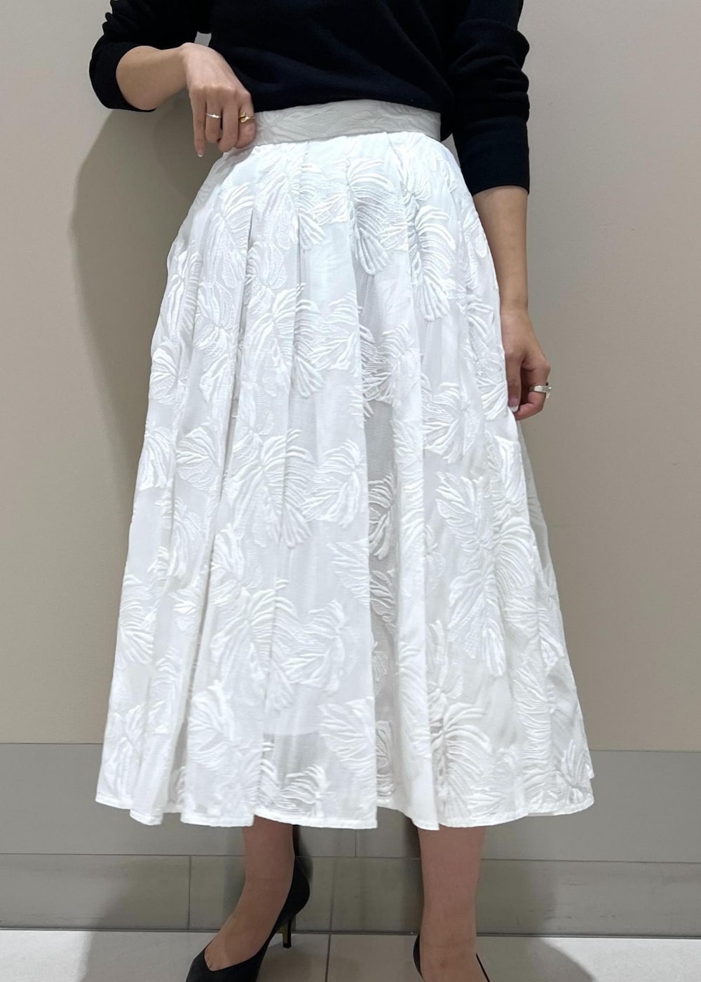 イエロー系のハンドバッグ、ホワイト系のスカート、ブラック系のニット/セーターを着用したレディースの冬コーディネートの5枚目の写真