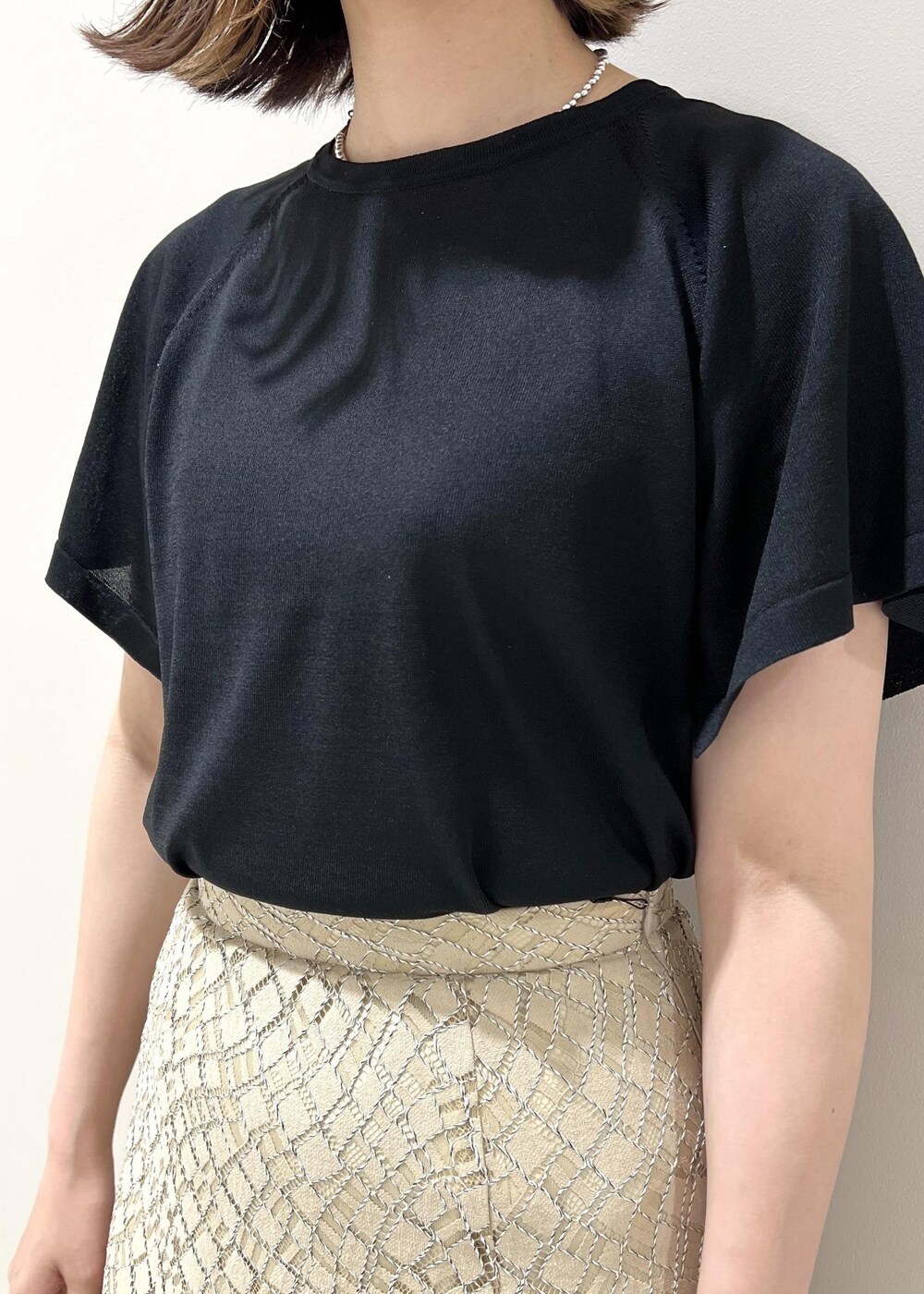 ベージュ系のハンドバッグ、ブラック系のニット/セーター、ベージュ系のスカートを着用したレディースの春コーディネートの6枚目の写真