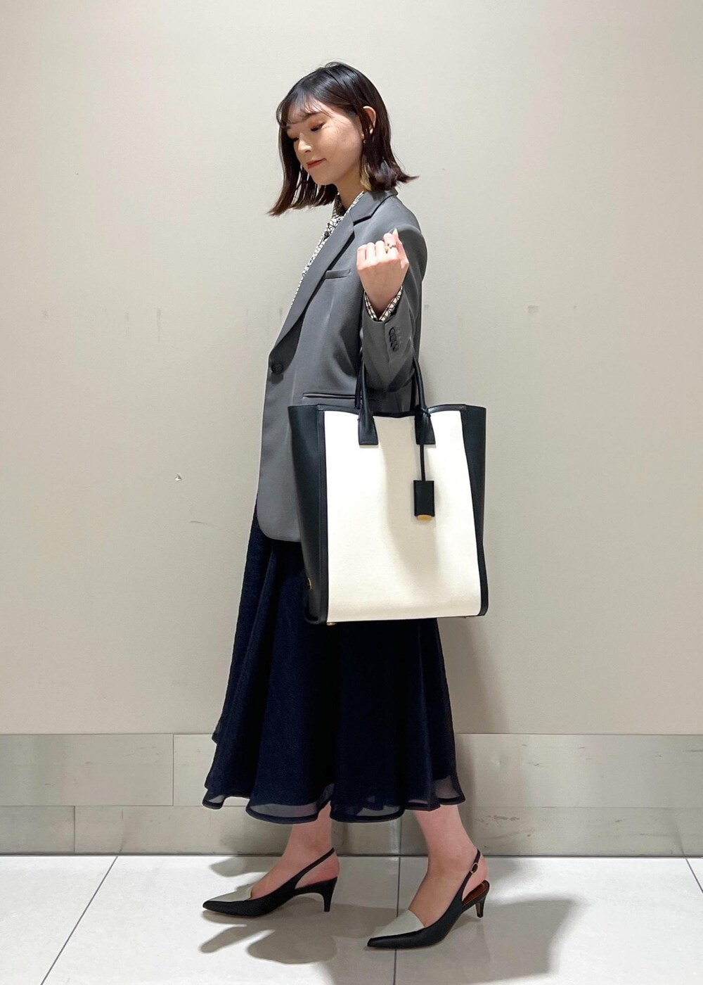 ブラック系のパンプス、ブルー系のスカート、ホワイト系のシャツ/ブラウスを着用したレディースの春コーディネートの3枚目の写真