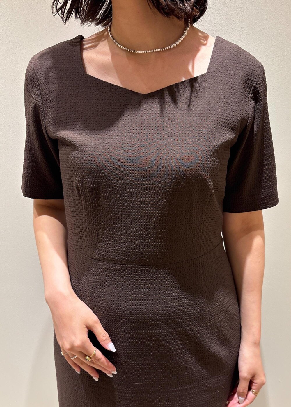 ホワイト系のハンドバッグ、ブラック系のサンダル、ブラウン系のワンピースを着用したレディースの夏コーディネートの5枚目の写真