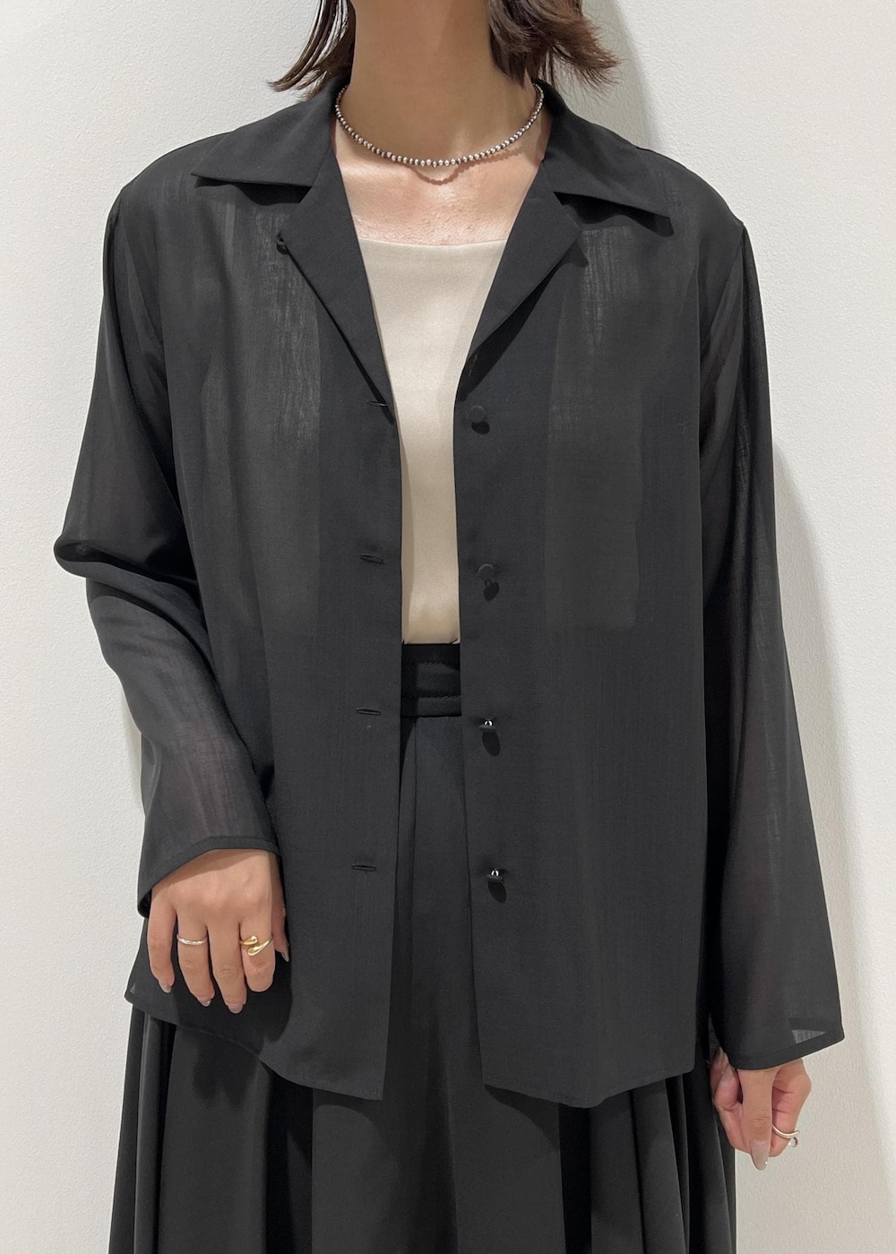 レッド系のハンドバッグ、ベージュ系のキャミソール、ブラック系のパンプスを着用したレディースの秋コーディネートの6枚目の写真