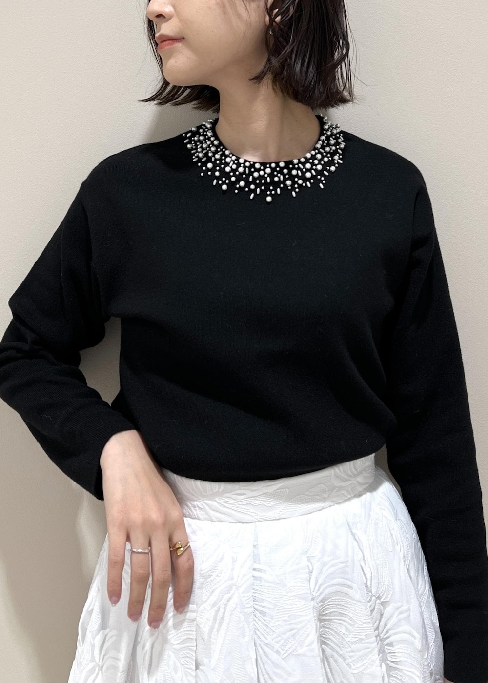 イエロー系のハンドバッグ、ホワイト系のスカート、ブラック系のニット/セーターを着用したレディースの冬コーディネートの4枚目の写真