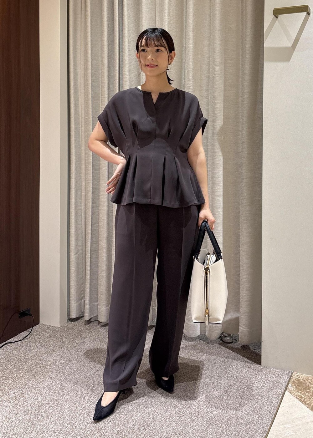 ブラック系のパンプス、ホワイト系のトートバッグ、ブラウン系のシャツ/ブラウスを着用したレディースの夏コーディネートの2枚目の写真