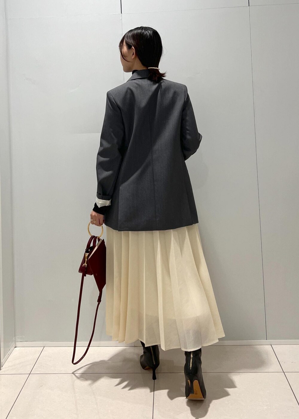 ブラック系のブーツ、ベージュ系のスカート、ブラック系のTシャツ/カットソーを着用したレディースの秋コーディネートの4枚目の写真