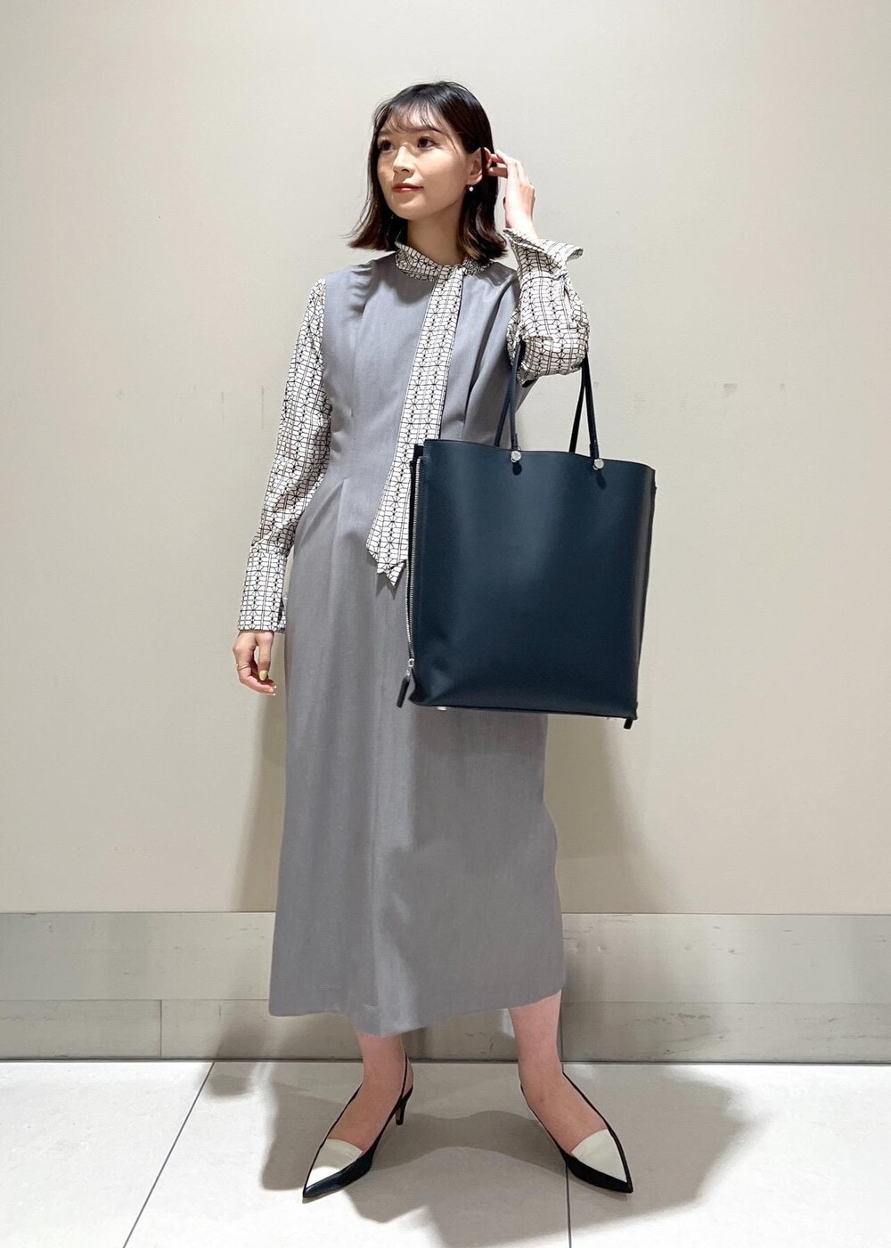 ホワイト系のシャツ/ブラウス、ブルー系のトートバッグ、ブラック系のパンプスを着用したレディースの春コーディネートの2枚目の写真