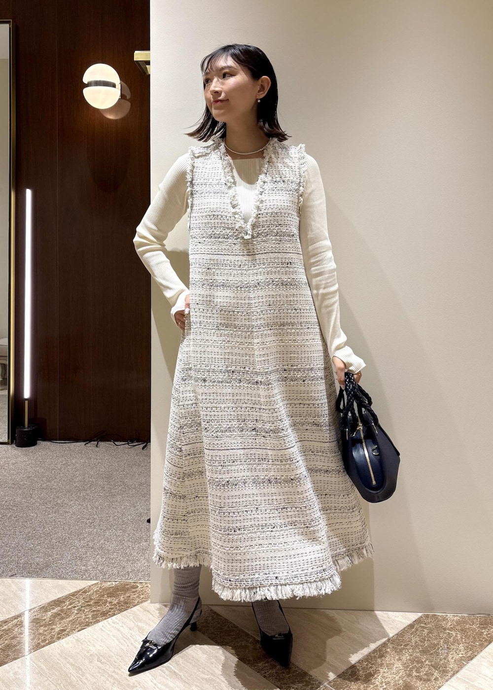 ブラック系のパンプス、ホワイト系のワンピース、ホワイト系のニット/セーターを着用したレディースの春コーディネートの2枚目の写真