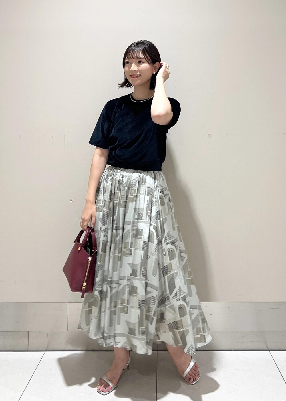 シルバー系のサンダル、レッド系のハンドバッグ、ブラック系のTシャツ/カットソーを着用したレディースの夏コーディネートの2枚目の写真