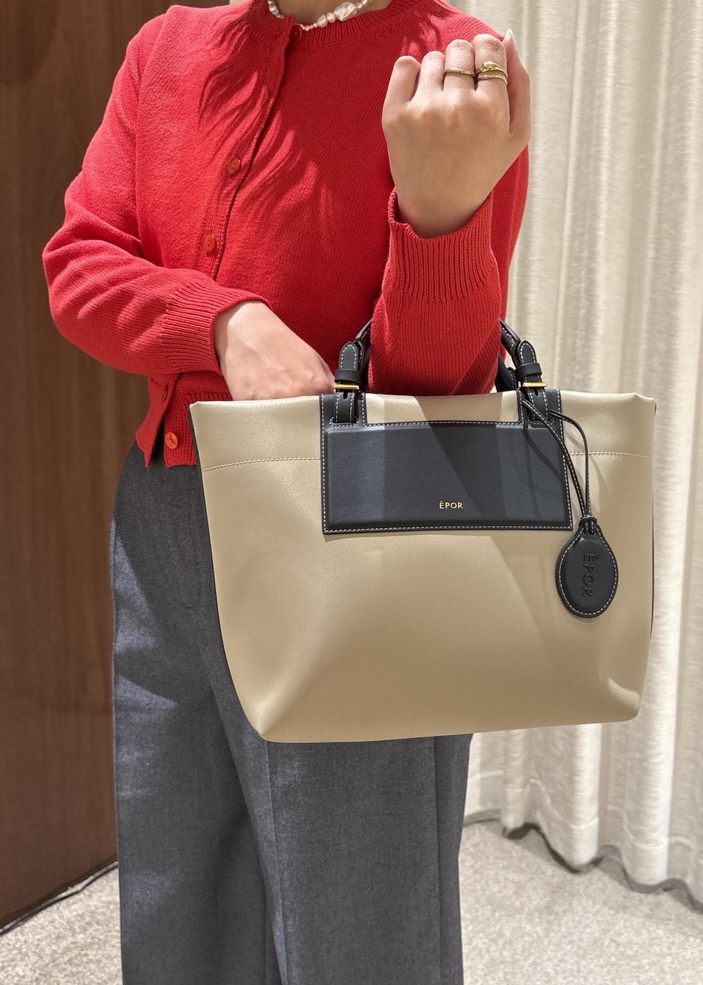 ベージュ系のトートバッグ、ブルー系のスラックス、レッド系のカーディガン/ボレロを着用したレディースの冬コーディネートの8枚目の写真