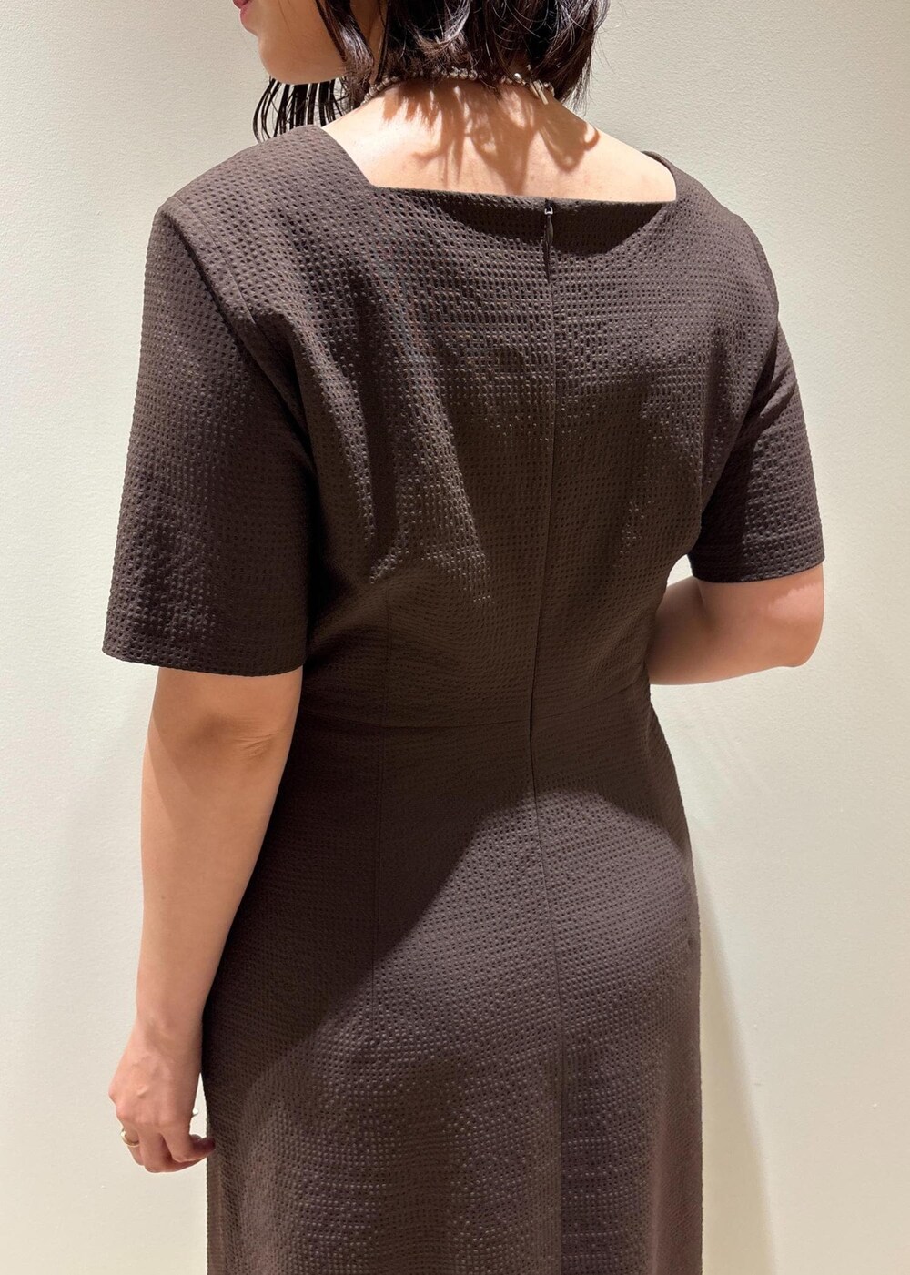 ホワイト系のハンドバッグ、ブラック系のサンダル、ブラウン系のワンピースを着用したレディースの夏コーディネートの6枚目の写真