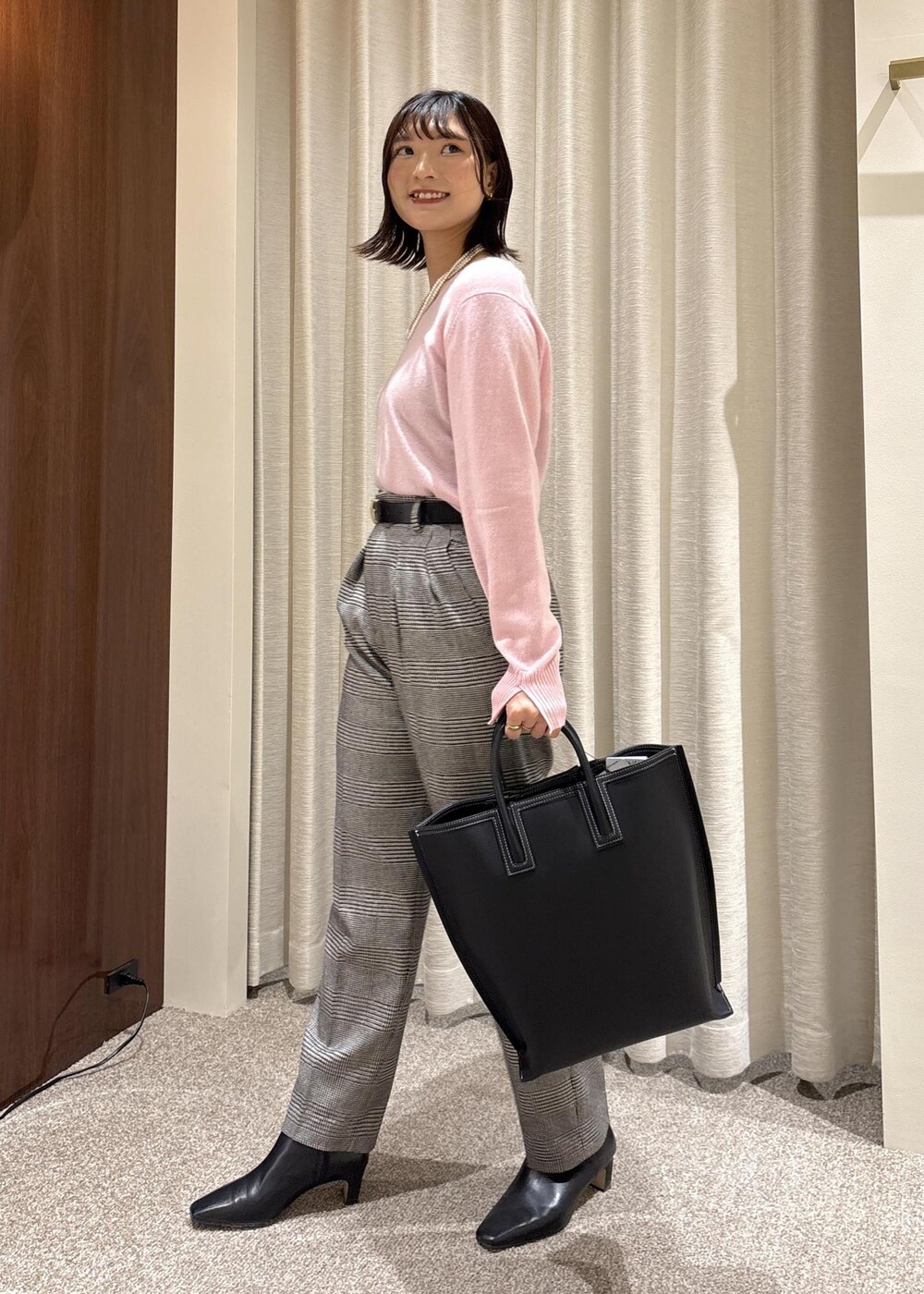 ブラック系のトートバッグ、ブラック系のブーツ、ピンク系のニット/セーターを着用したレディースの秋コーディネートの3枚目の写真