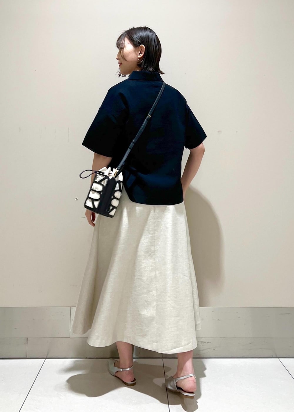 ブラック系のハンドバッグ、シルバー系のパンプス、ブルー系のニット/セーターを着用したレディースの春コーディネートの4枚目の写真