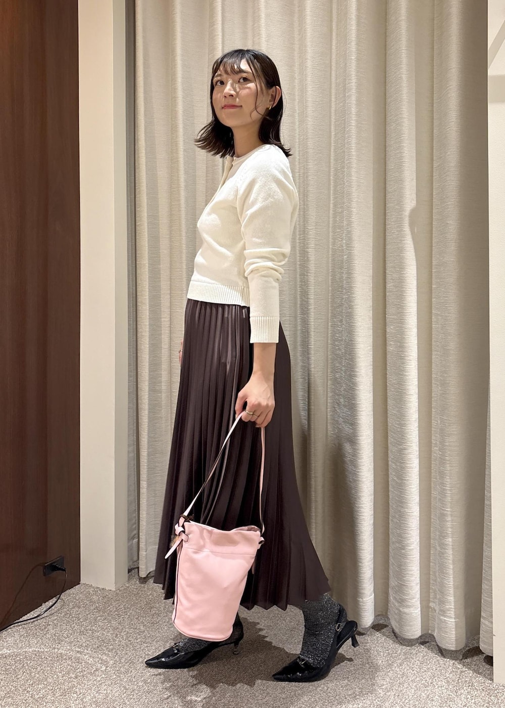 ピンク系のハンドバッグ、ブラウン系のスカート、ホワイト系のニット/セーターを着用したレディースの春コーディネートの3枚目の写真