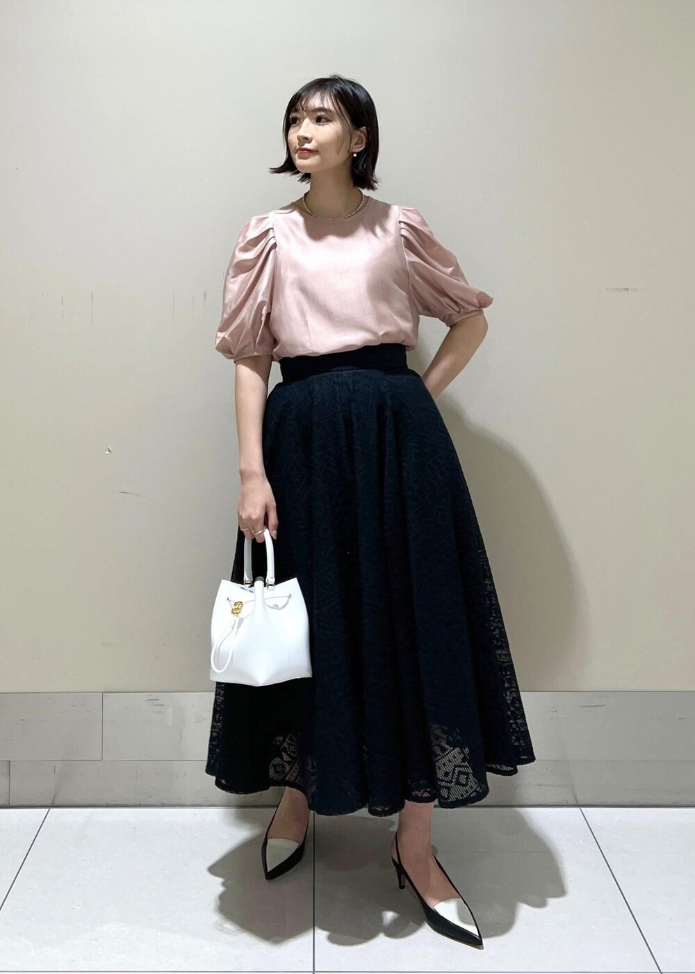 ホワイト系のハンドバッグ、ブラック系のパンプス、ピンク系のシャツ/ブラウスを着用したレディースの春コーディネートの3枚目の写真