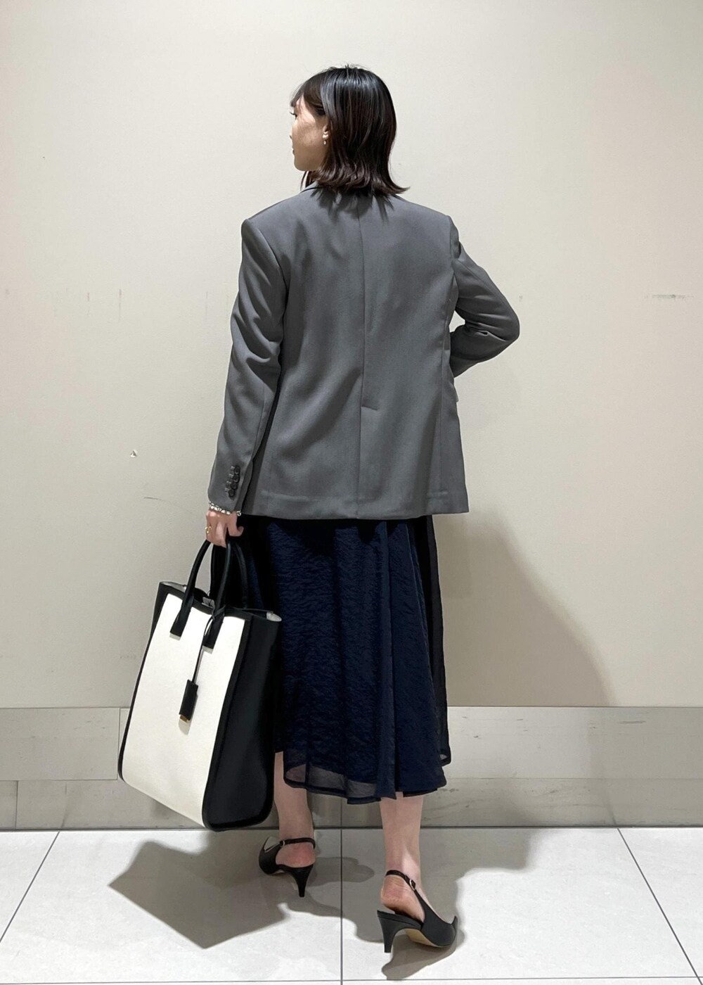 ブラック系のパンプス、ブルー系のスカート、ホワイト系のシャツ/ブラウスを着用したレディースの春コーディネートの4枚目の写真