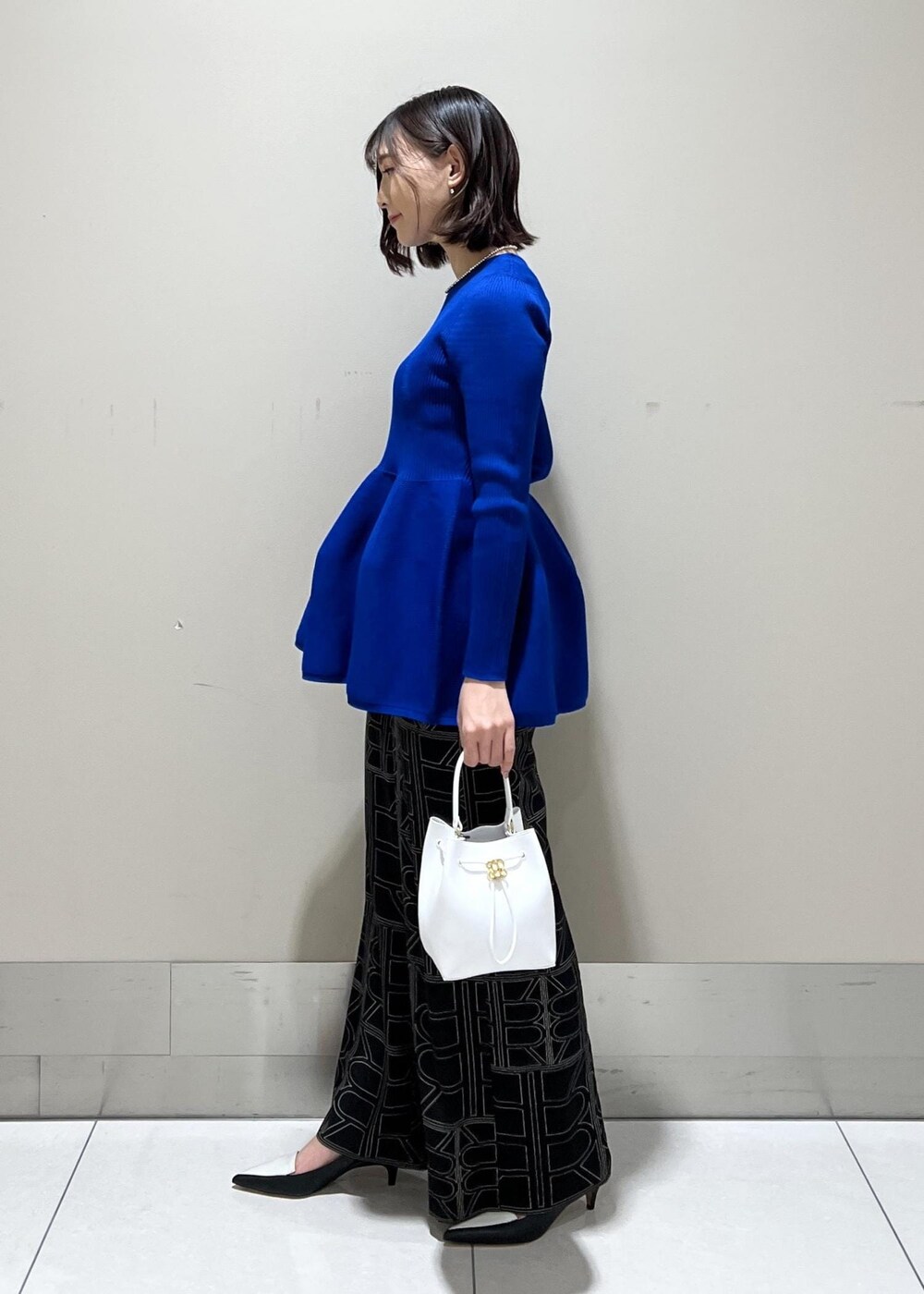 ホワイト系のハンドバッグ、ブラック系のその他パンツ、ブルー系のニット/セーターを着用したレディースの冬コーディネートの3枚目の写真