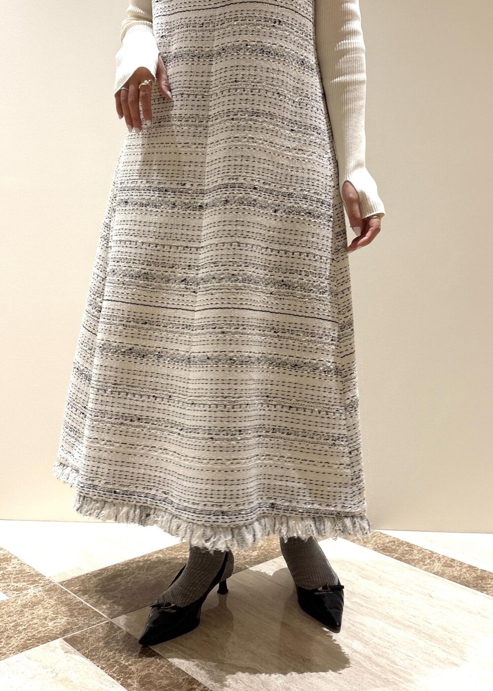 ブラック系のパンプス、ホワイト系のワンピース、ホワイト系のニット/セーターを着用したレディースの春コーディネートの6枚目の写真