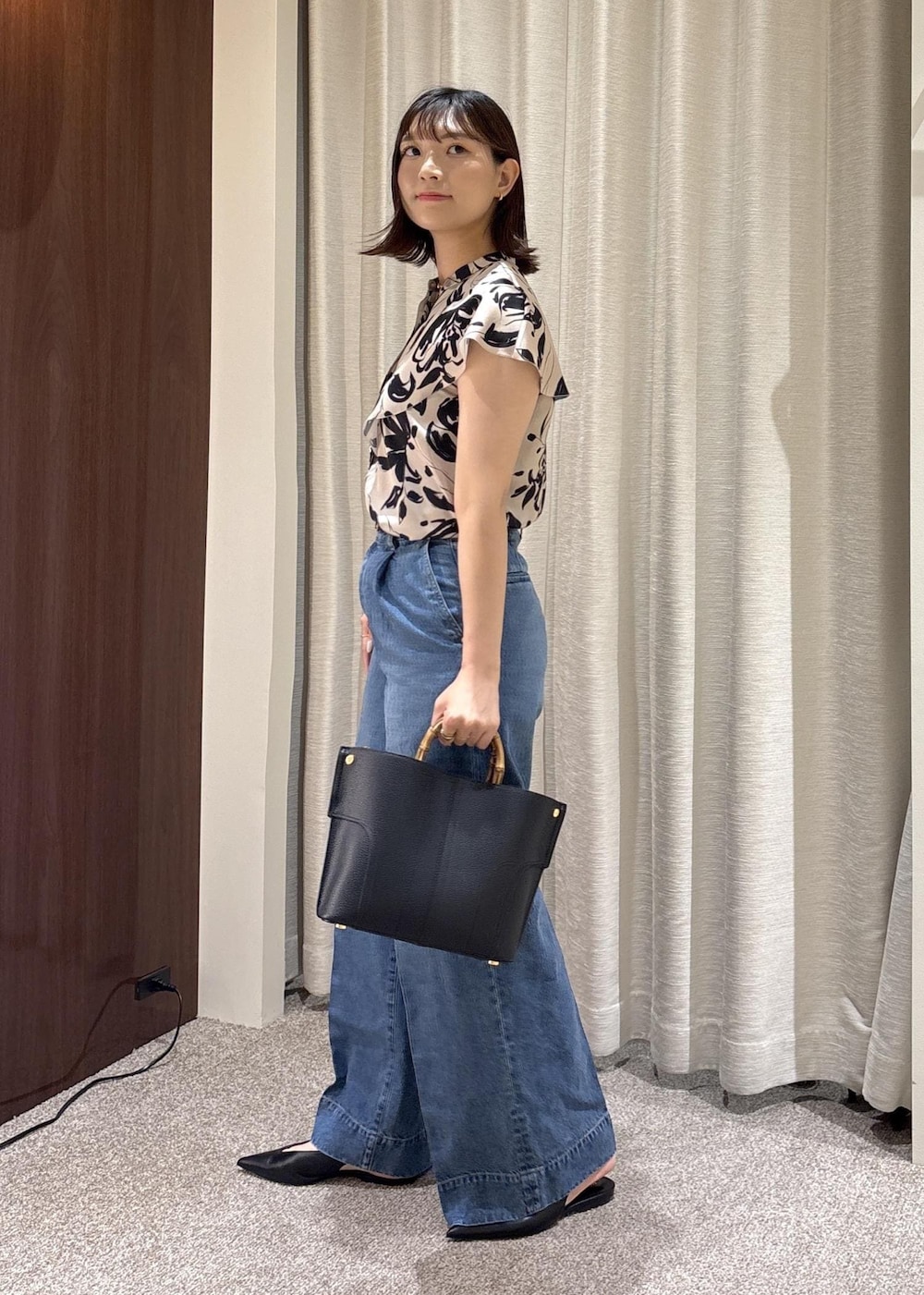 ブラック系のパンプス、ブラック系のハンドバッグ、ブルー系のデニムパンツを着用したレディースの夏コーディネートの3枚目の写真