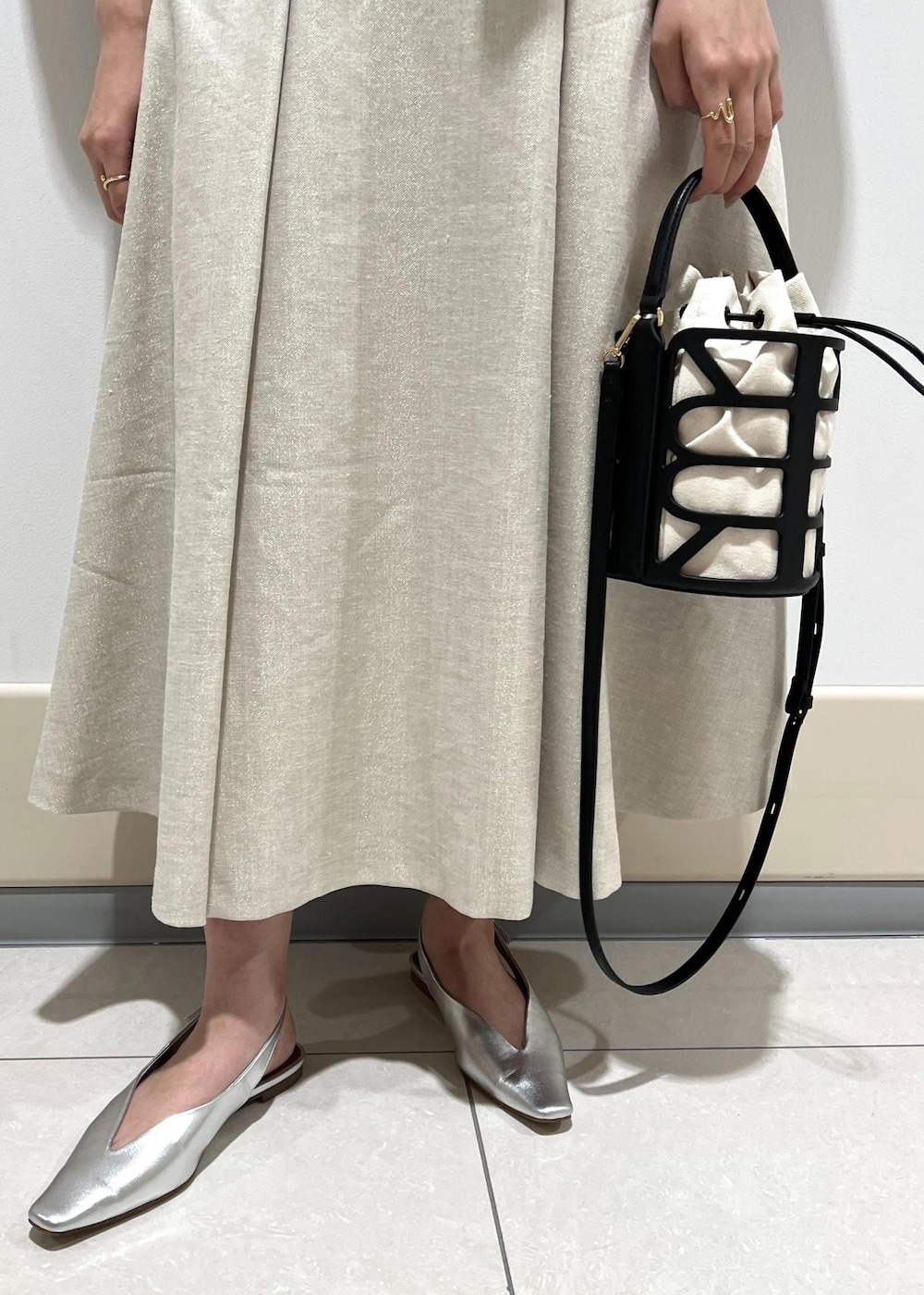 ブラック系のハンドバッグ、シルバー系のパンプス、ブルー系のニット/セーターを着用したレディースの春コーディネートの8枚目の写真