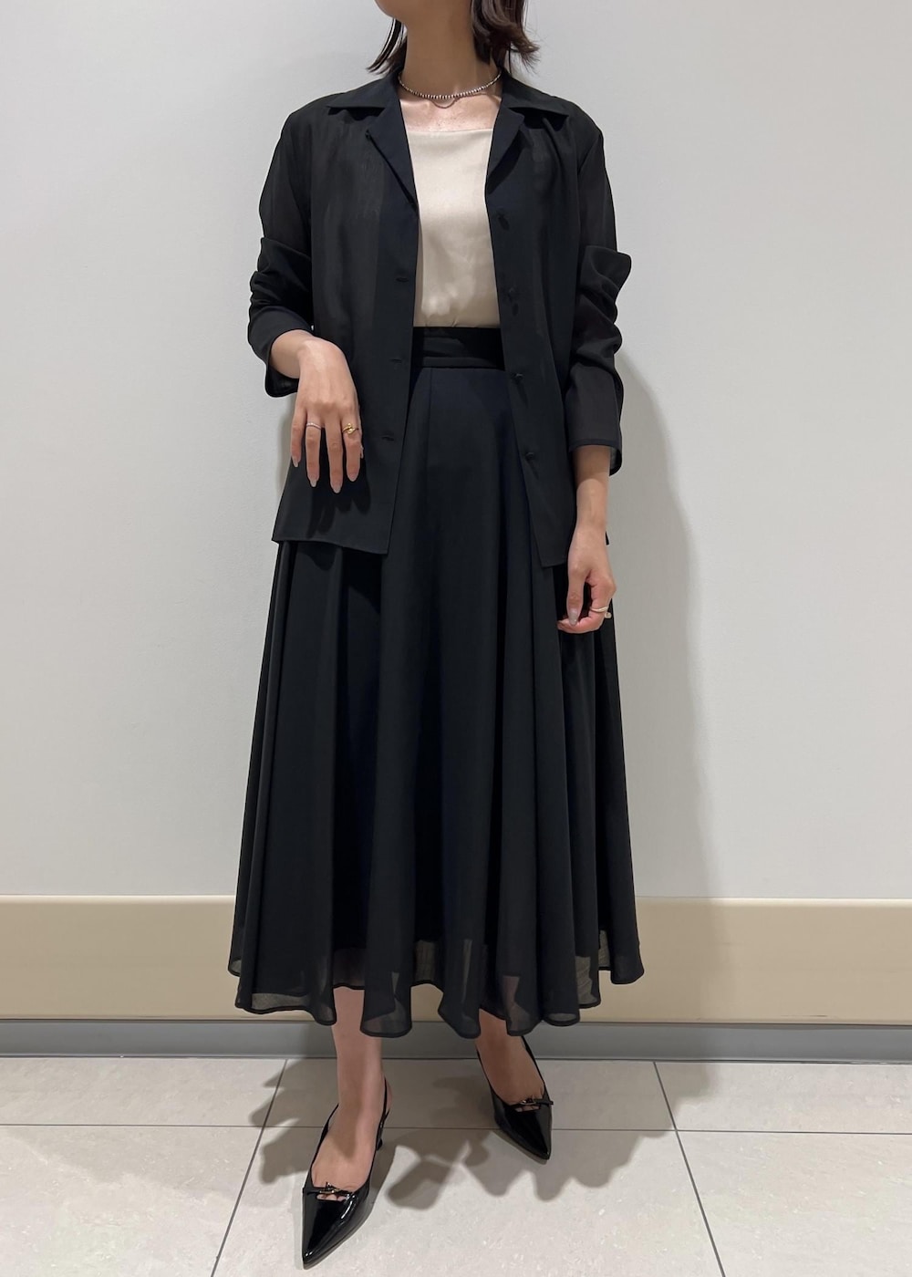 レッド系のハンドバッグ、ベージュ系のキャミソール、ブラック系のパンプスを着用したレディースの秋コーディネートの5枚目の写真