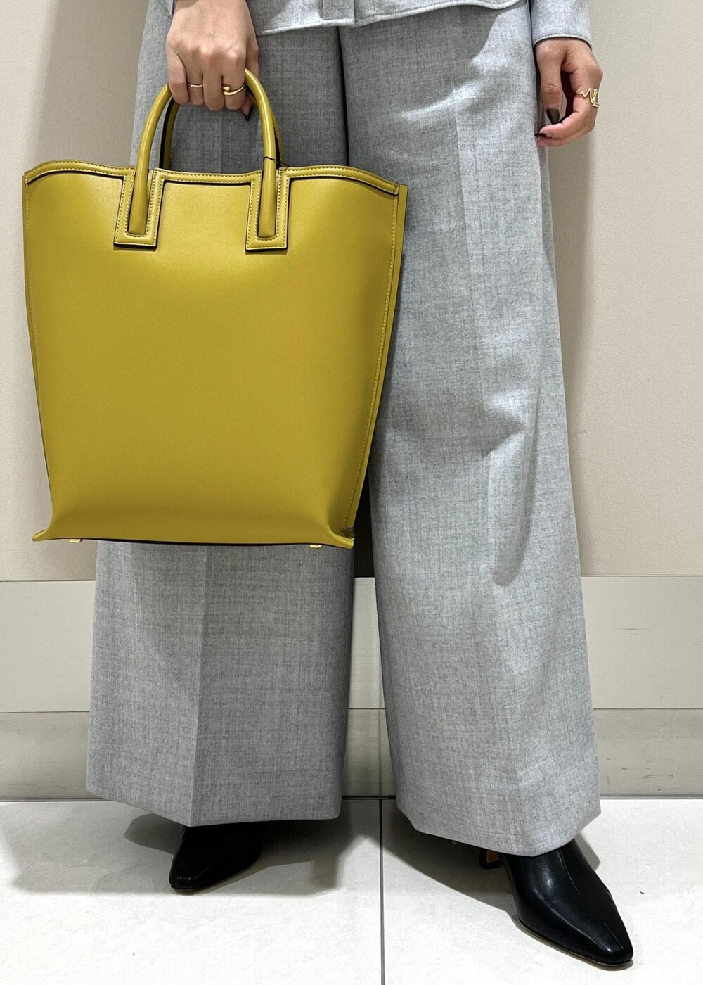 イエロー系のトートバッグ、ブラック系のブーツ、グレー系のシャツ/ブラウスを着用したレディースの秋コーディネートの9枚目の写真