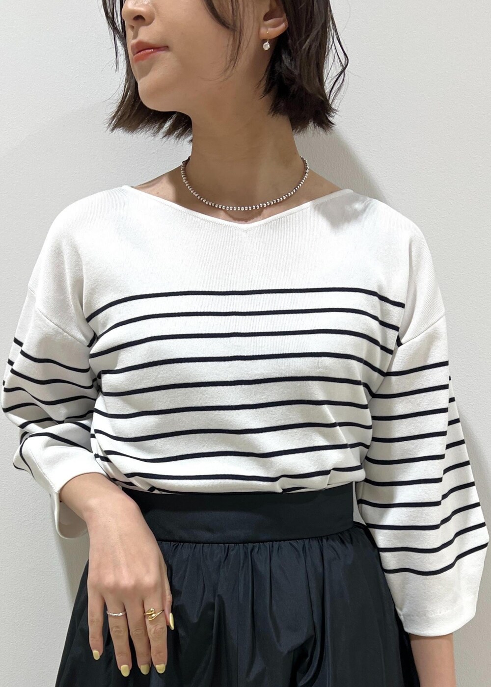 グリーン系のハンドバッグ、ホワイト系のパンプス、ブラック系のスカートを着用したレディースの春コーディネートの6枚目の写真