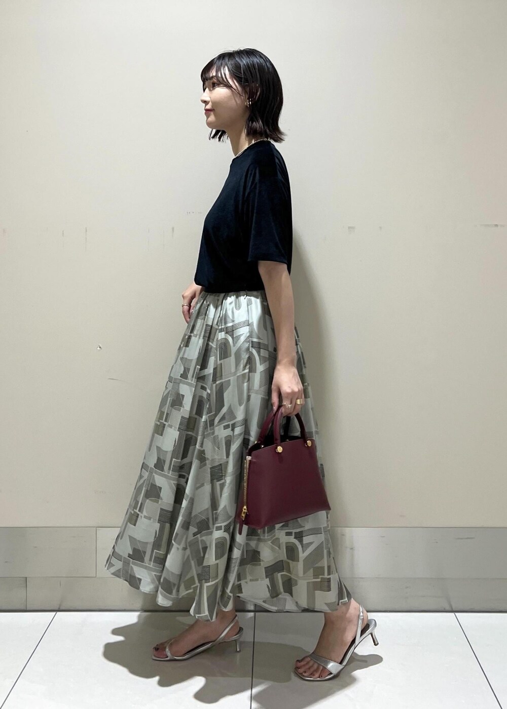 シルバー系のサンダル、レッド系のハンドバッグ、ブラック系のTシャツ/カットソーを着用したレディースの夏コーディネートの4枚目の写真