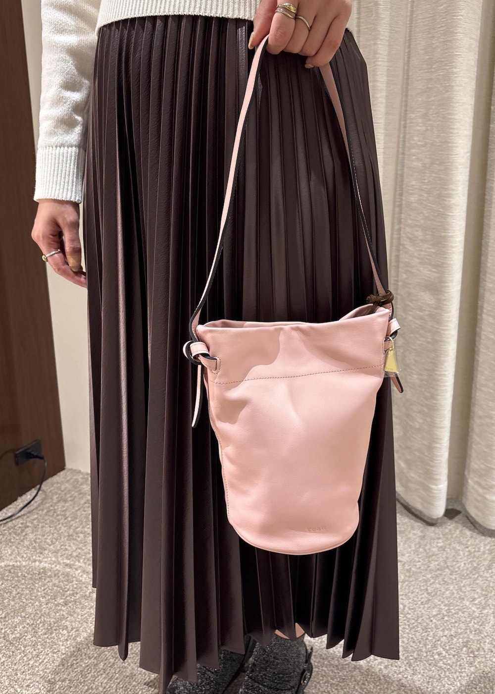 ピンク系のハンドバッグ、ブラウン系のスカート、ホワイト系のニット/セーターを着用したレディースの春コーディネートの7枚目の写真