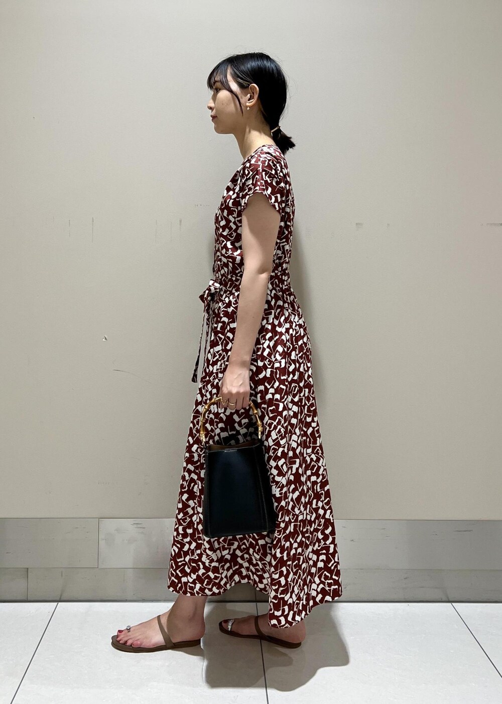 ブラック系のハンドバッグ、ベージュ系のサンダル、レッド系のワンピースを着用したレディースの夏コーディネートの2枚目の写真