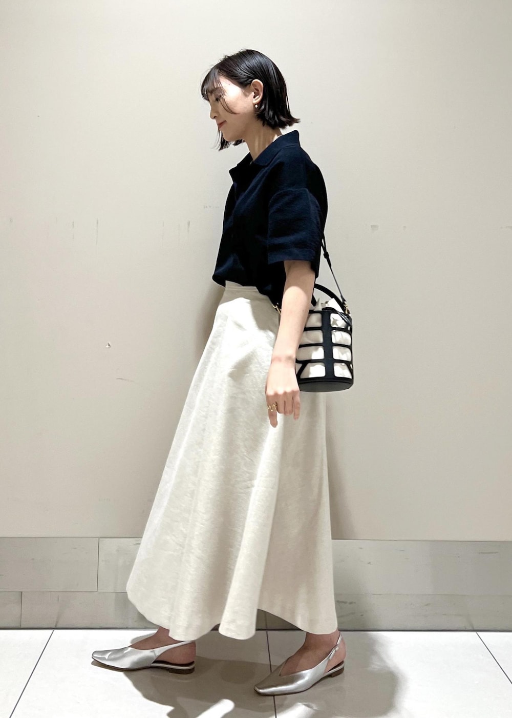 ブラック系のハンドバッグ、シルバー系のパンプス、ブルー系のニット/セーターを着用したレディースの春コーディネートの3枚目の写真