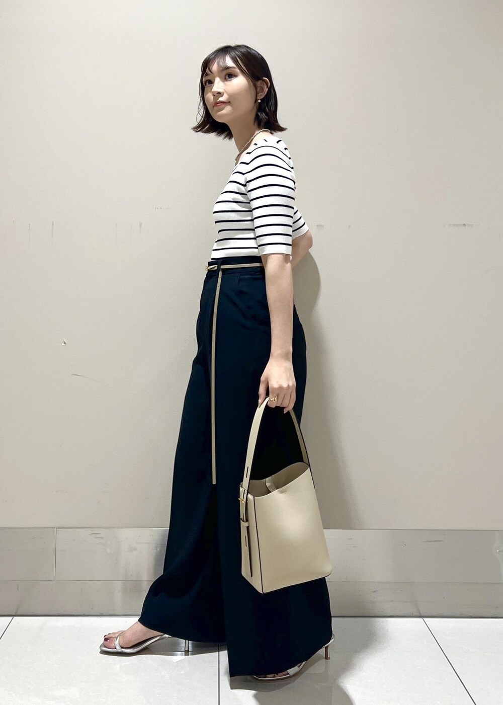 シルバー系のサンダル、ホワイト系のTシャツ/カットソー、ベージュ系のハンドバッグを着用したレディースの春コーディネートの2枚目の写真