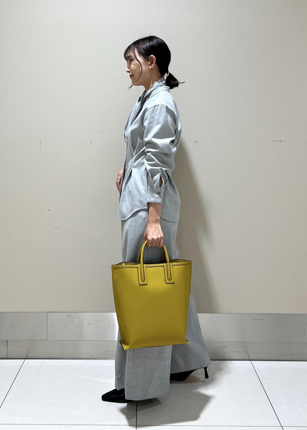 イエロー系のトートバッグ、ブラック系のブーツ、グレー系のシャツ/ブラウスを着用したレディースの秋コーディネートの3枚目の写真