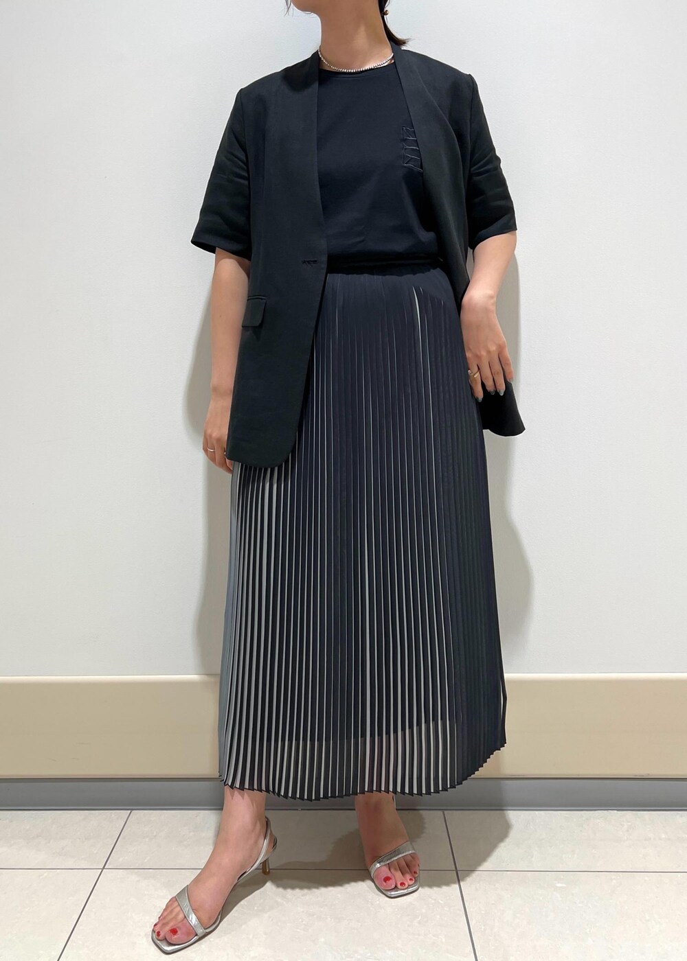 シルバー系のサンダル、グリーン系のショルダーバッグ、ブラック系のスカートを着用したレディースの夏コーディネートの5枚目の写真