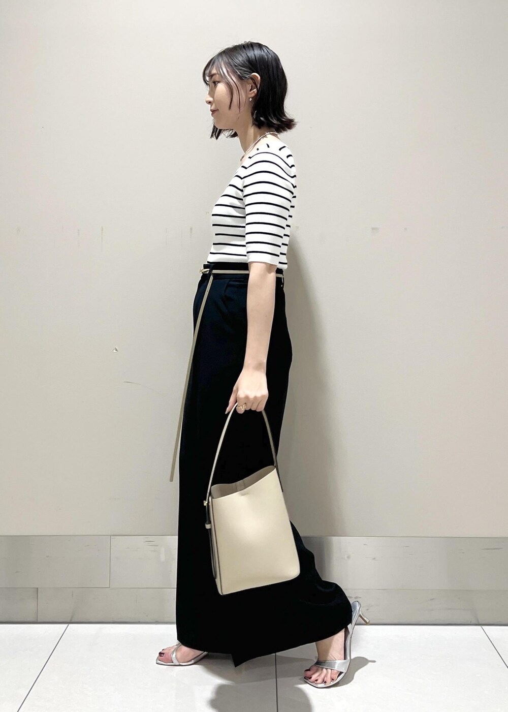 シルバー系のサンダル、ホワイト系のTシャツ/カットソー、ベージュ系のハンドバッグを着用したレディースの春コーディネートの3枚目の写真