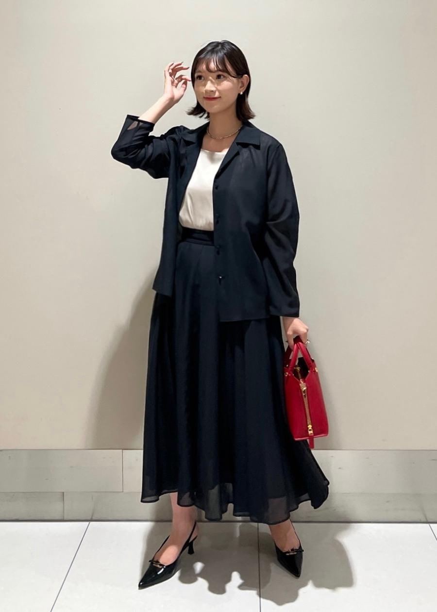 レッド系のハンドバッグ、ベージュ系のキャミソール、ブラック系のパンプスを着用したレディースの秋コーディネートの2枚目の写真