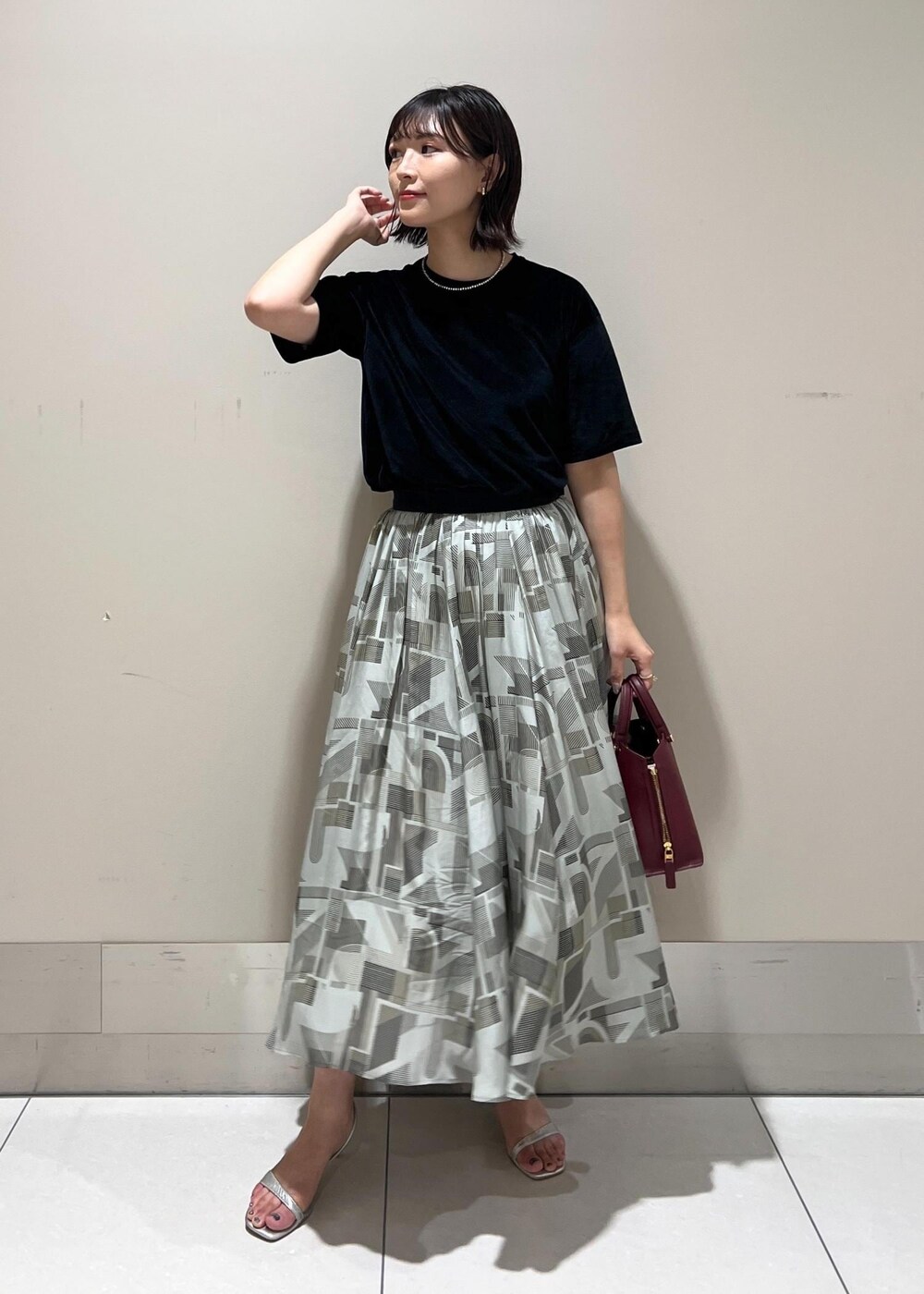 シルバー系のサンダル、レッド系のハンドバッグ、ブラック系のTシャツ/カットソーを着用したレディースの夏コーディネートの3枚目の写真