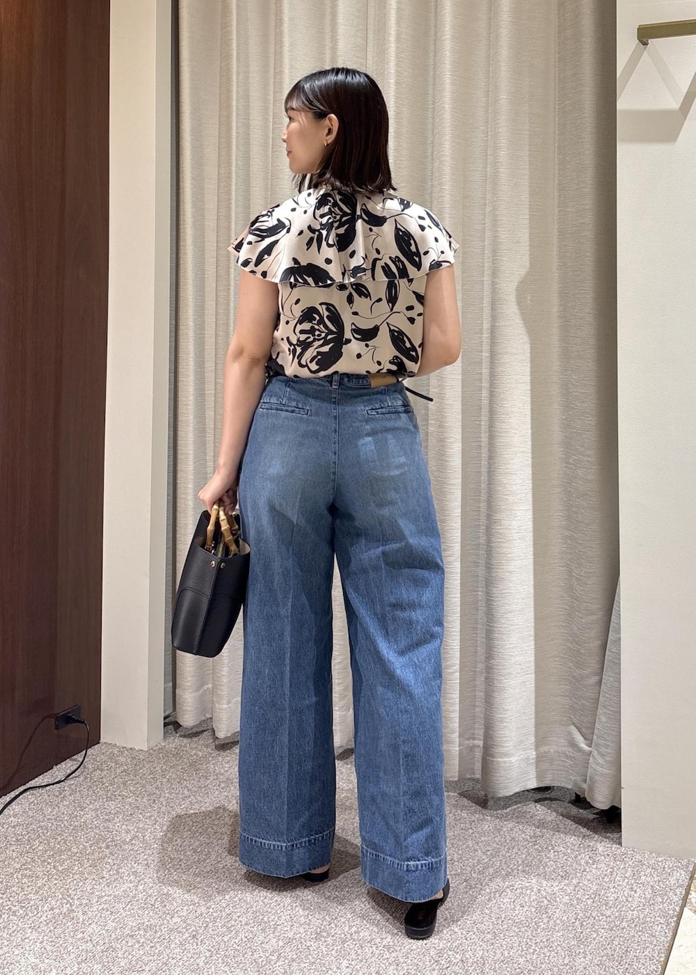 ブラック系のパンプス、ブラック系のハンドバッグ、ブルー系のデニムパンツを着用したレディースの夏コーディネートの4枚目の写真