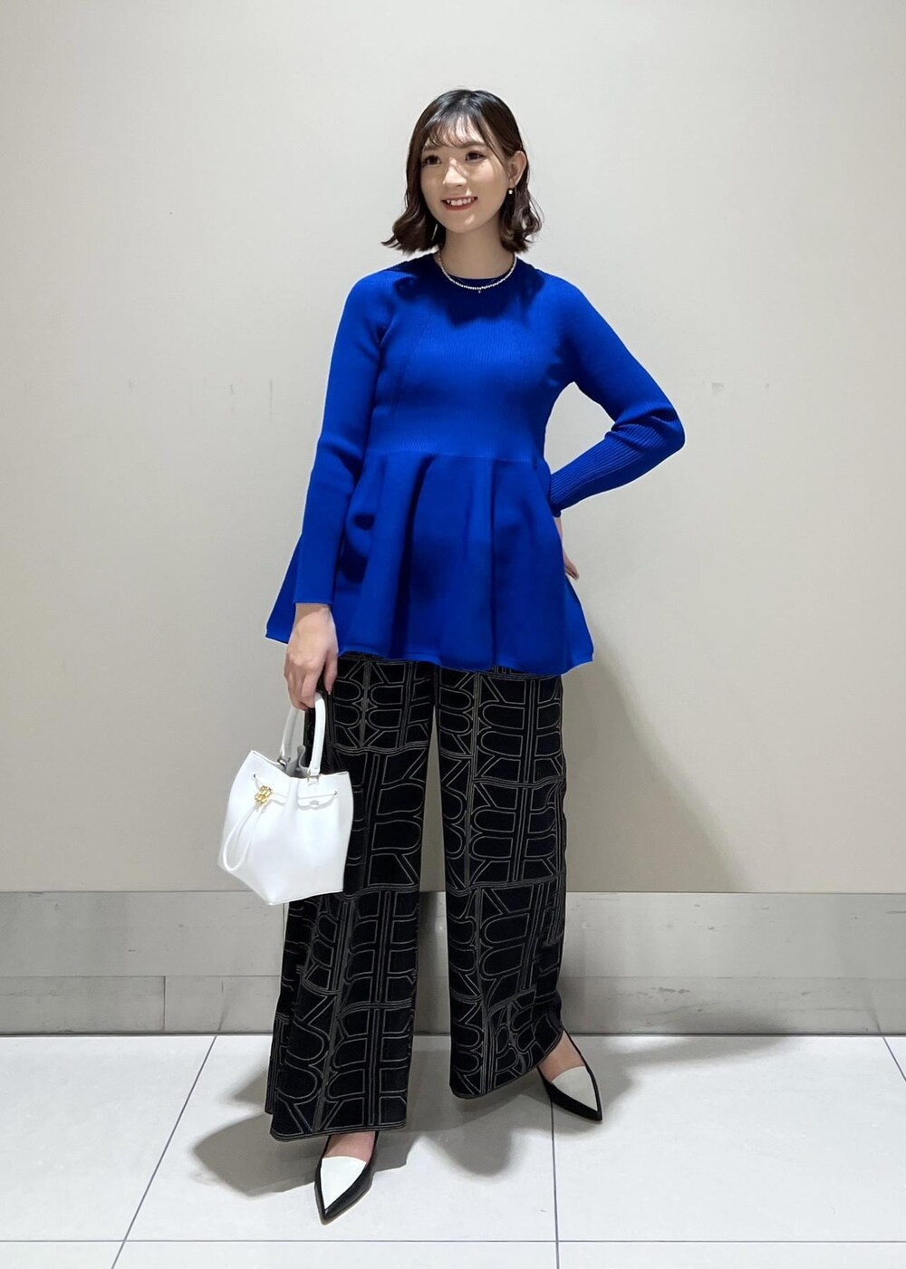 ホワイト系のハンドバッグ、ブラック系のその他パンツ、ブルー系のニット/セーターを着用したレディースの冬コーディネートの2枚目の写真