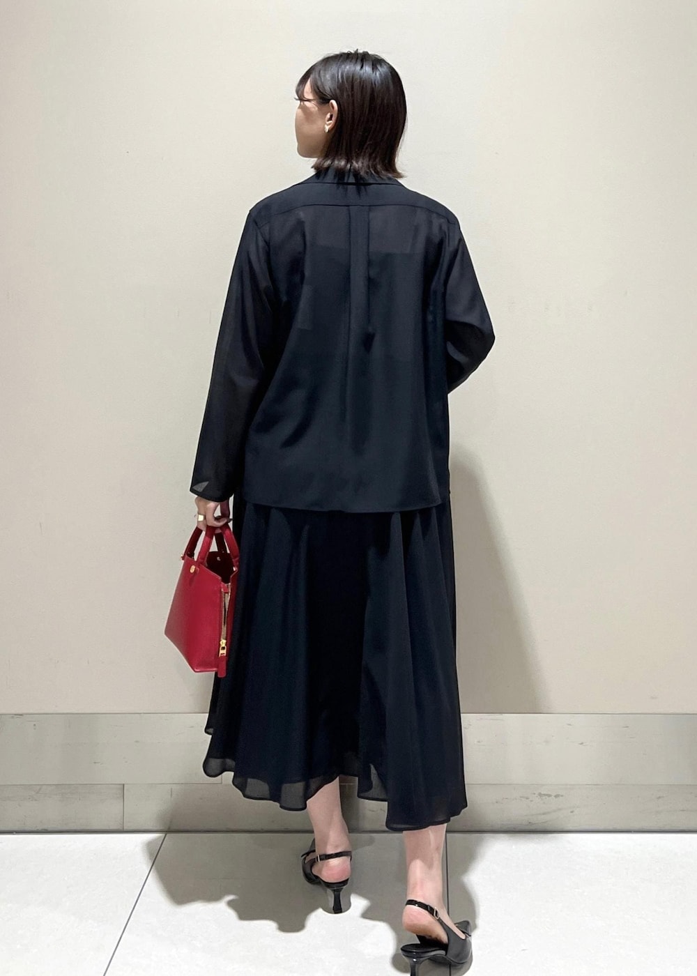 レッド系のハンドバッグ、ベージュ系のキャミソール、ブラック系のパンプスを着用したレディースの秋コーディネートの4枚目の写真