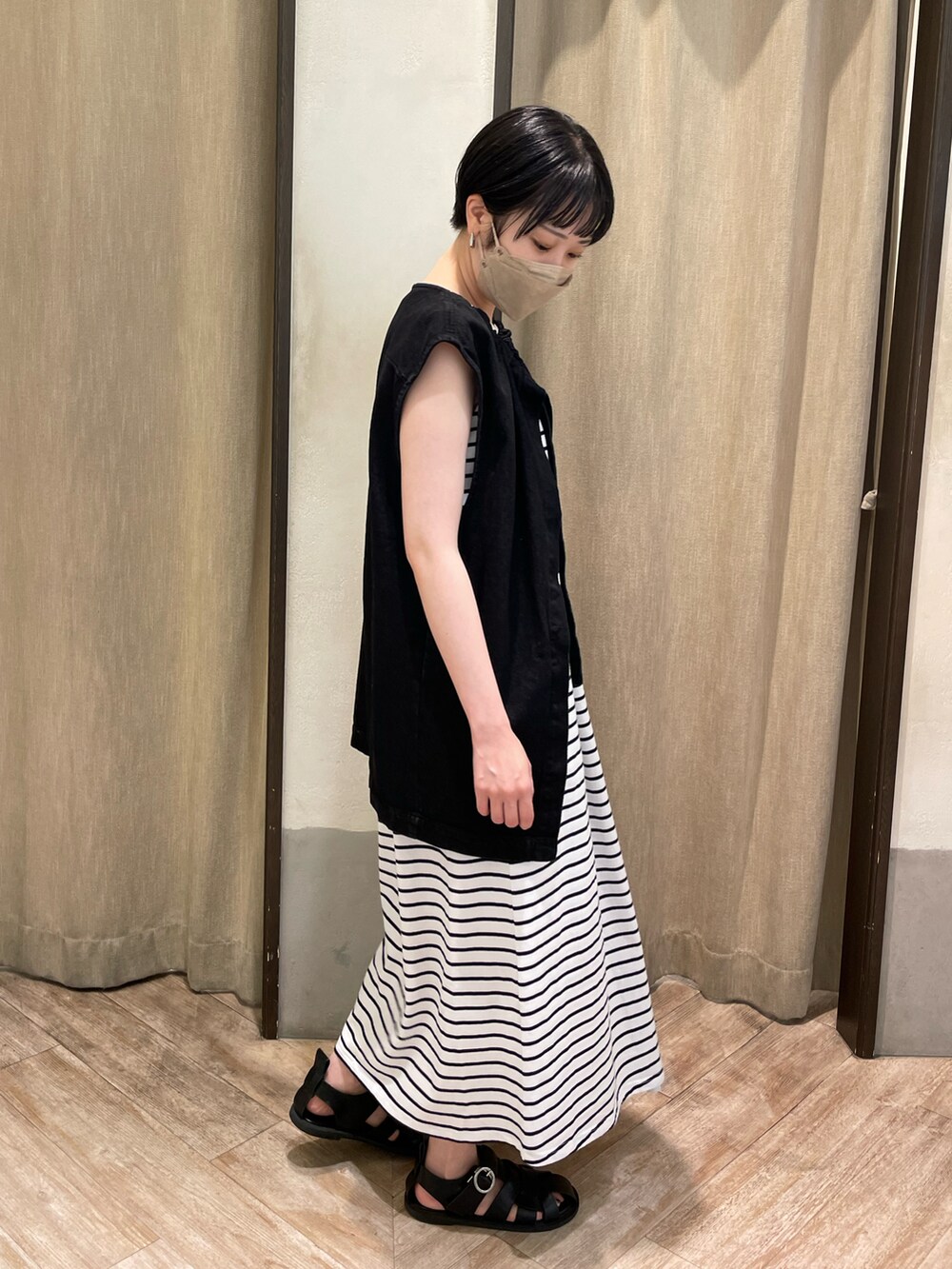 ブラック系のベスト、ホワイト系のワンピース、ブラック系のサンダルを着用したレディースの夏コーディネートの2枚目の写真