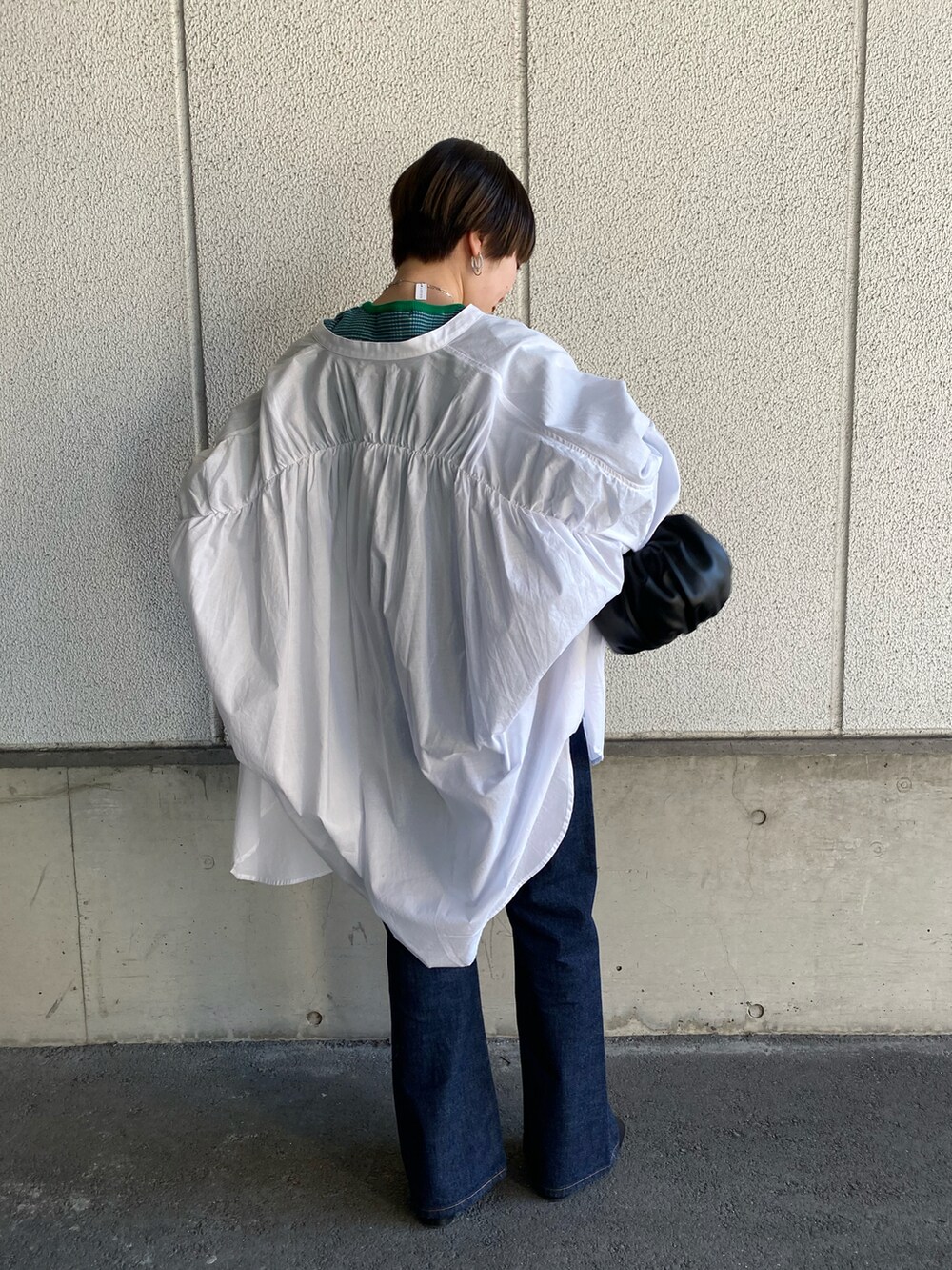 グリーン系のニット/セーター、ホワイト系のシャツ/ブラウス、ブルー系のデニムパンツを着用したレディースの春コーディネートの3枚目の写真