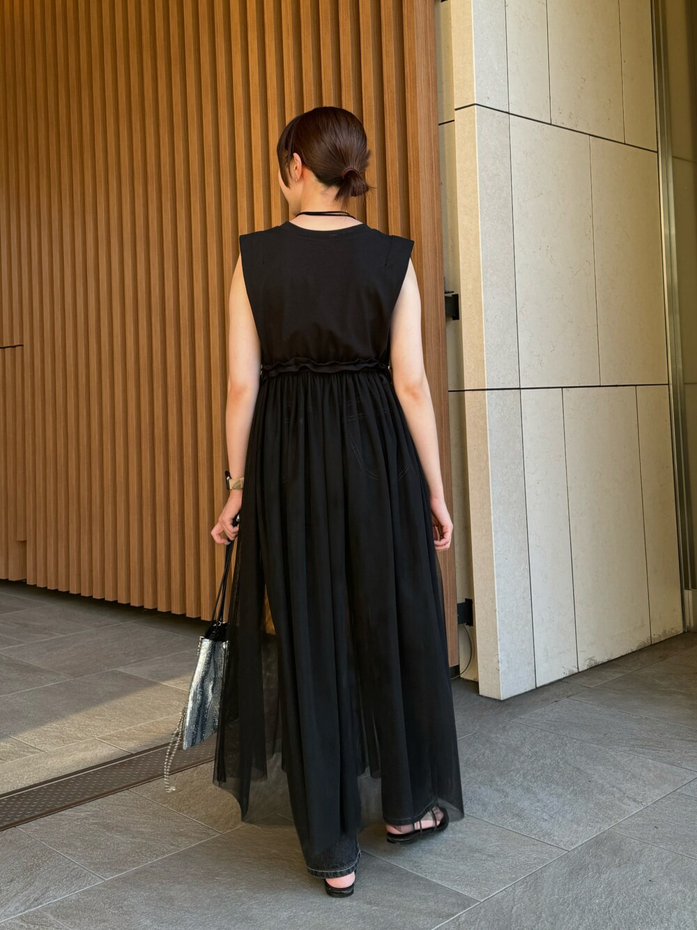 ブラック系のワンピース、ブラック系のデニムパンツ、シルバー系のショルダーバッグを着用したレディースの夏コーディネートの2枚目の写真