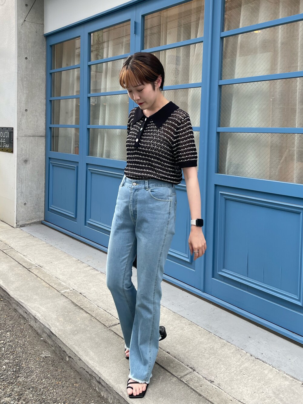 ブラック系のニット/セーター、ブルー系のデニムパンツ、ホワイト系のサンダルを着用したレディースの夏コーディネートの2枚目の写真