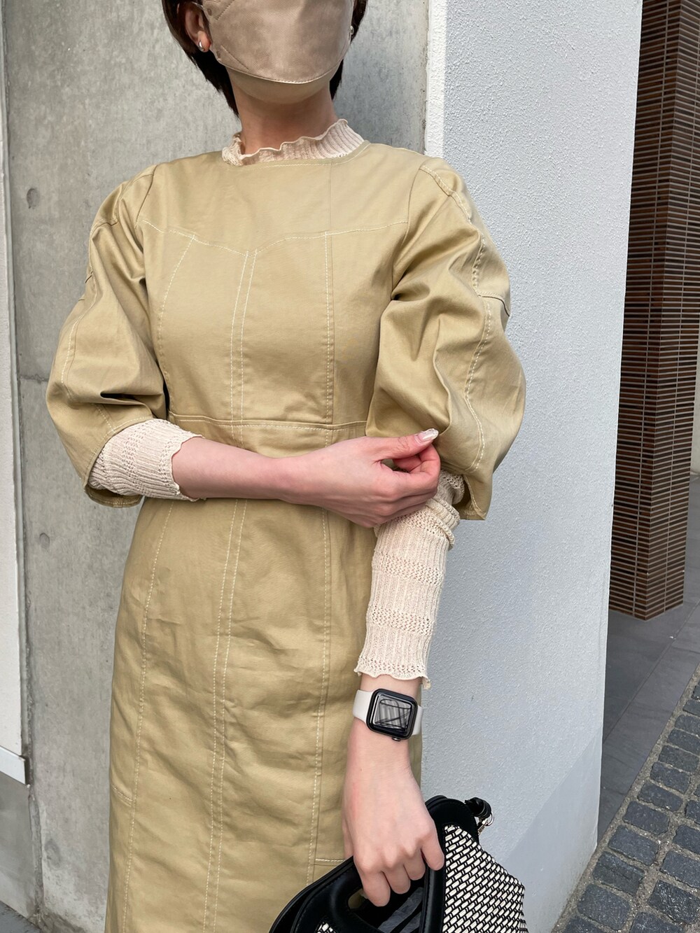 ベージュ系のワンピース、ホワイト系のニット/セーター、ブラック系のショルダーバッグを着用したレディースの春コーディネートの3枚目の写真