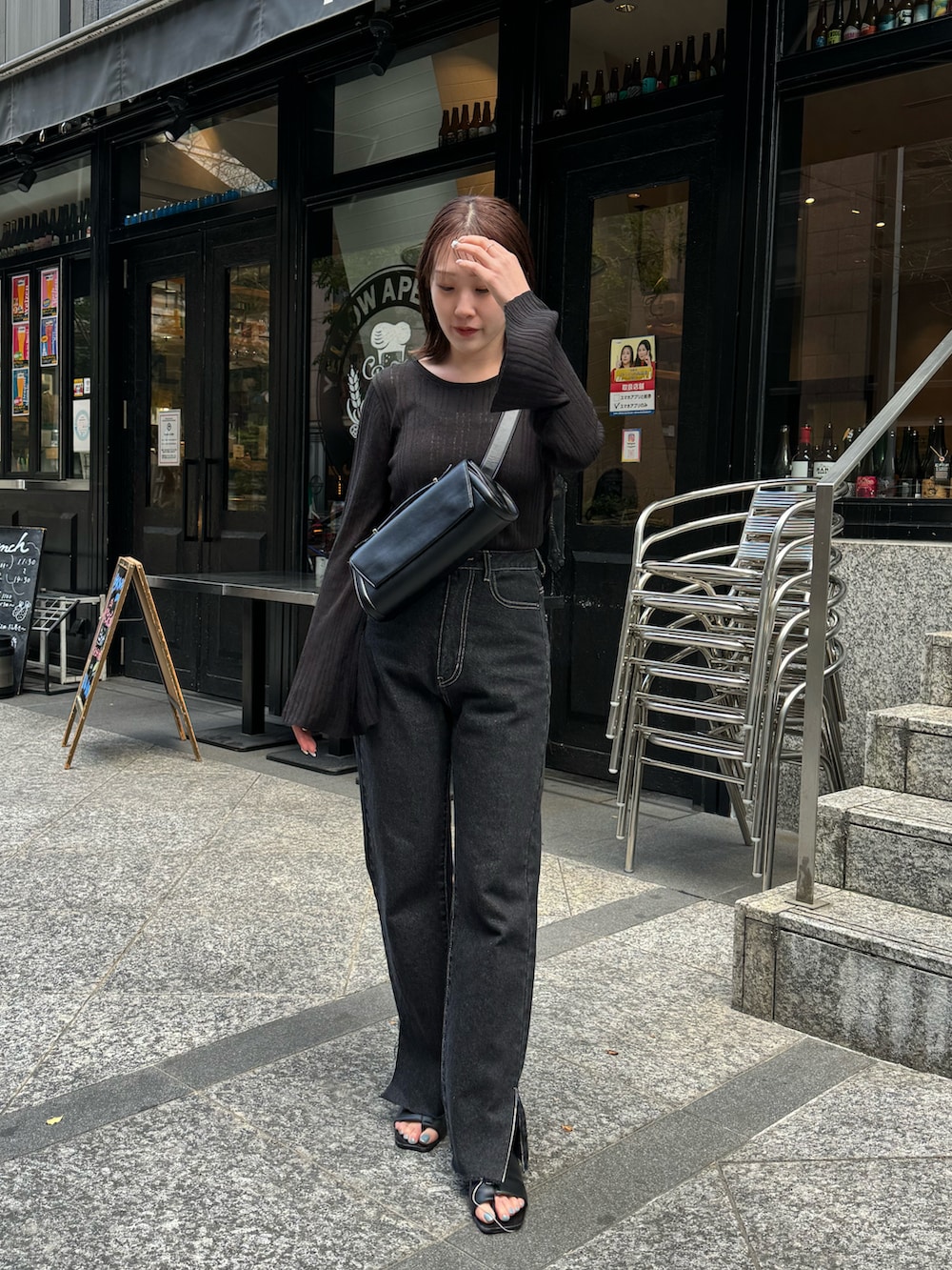 ブラック系のニット/セーター、ブラック系のショルダーバッグ、ブラック系のデニムパンツを着用したレディースの春コーディネートの2枚目の写真