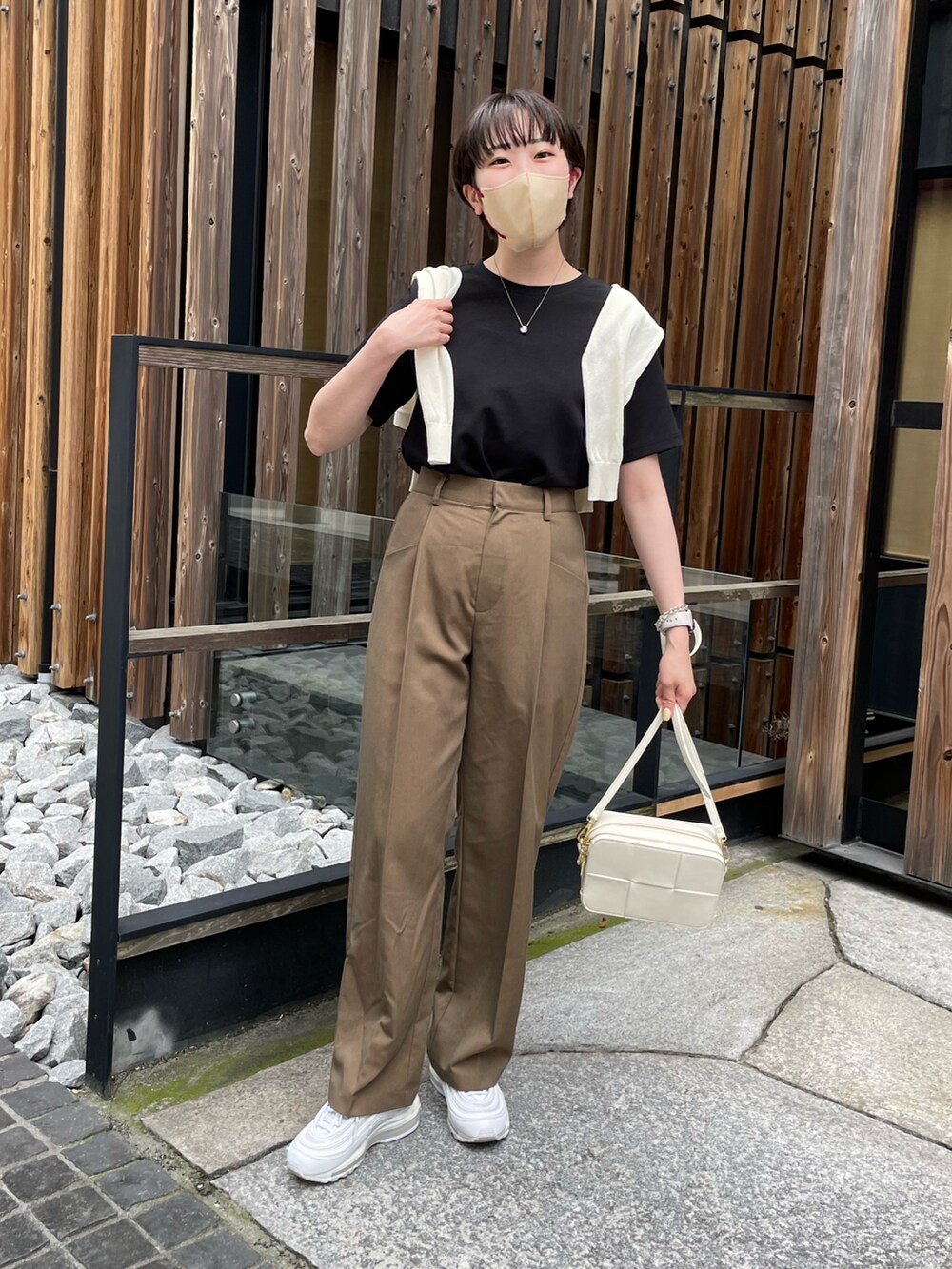 ブラック系のTシャツ/カットソー、ブラウン系のスラックス、ホワイト系のスニーカーを着用したレディースの春コーディネートの2枚目の写真