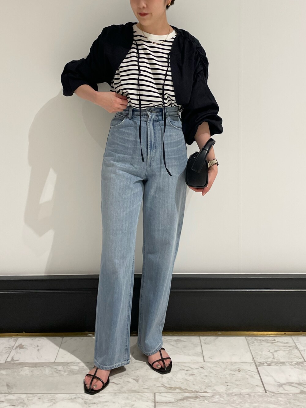 ブラック系のトップス、ブラック系のTシャツ/カットソー、ブルー系のデニムパンツを着用したレディースの春コーディネートの2枚目の写真