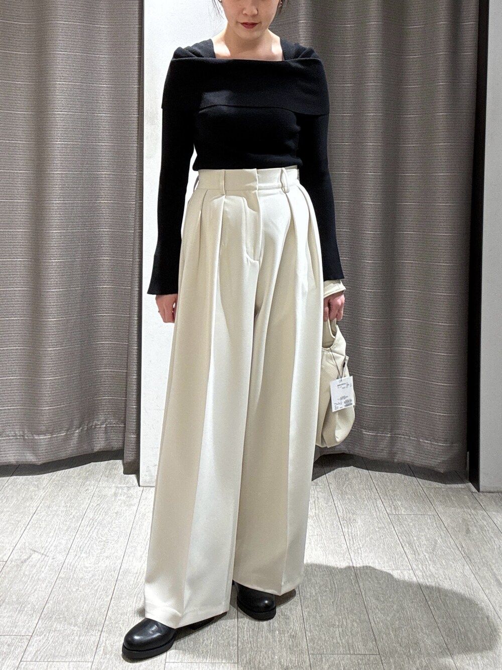 ホワイト系のハンドバッグ、ブラック系のニット/セーター、ホワイト系のその他パンツを着用したレディースの冬コーディネートの2枚目の写真